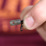 Vezmete jednu z čepiček z balení Drop Off Lead Plugs a navléknete ji na očko obratlíku podle obrázku