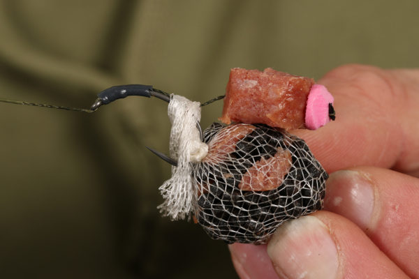 16. Nyní háček prostrčíme PVA sáčkem a přebytečné PVA omotáme kolem viditelného návazce a hrotu háčku